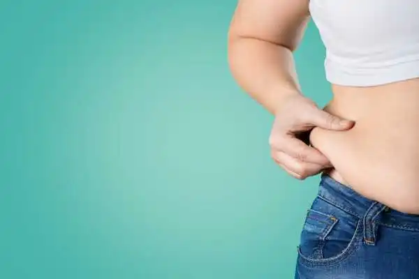 Image of woman pinching her love handles to show weight gain Stockport